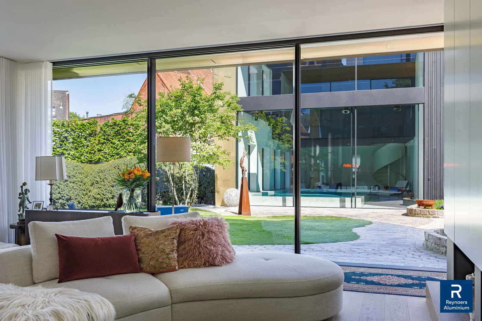 Fijne aluminium raamprofielen verbinden een leefruimte met de tuin. Inspiratiebeeld van Reynaers Aluminium.